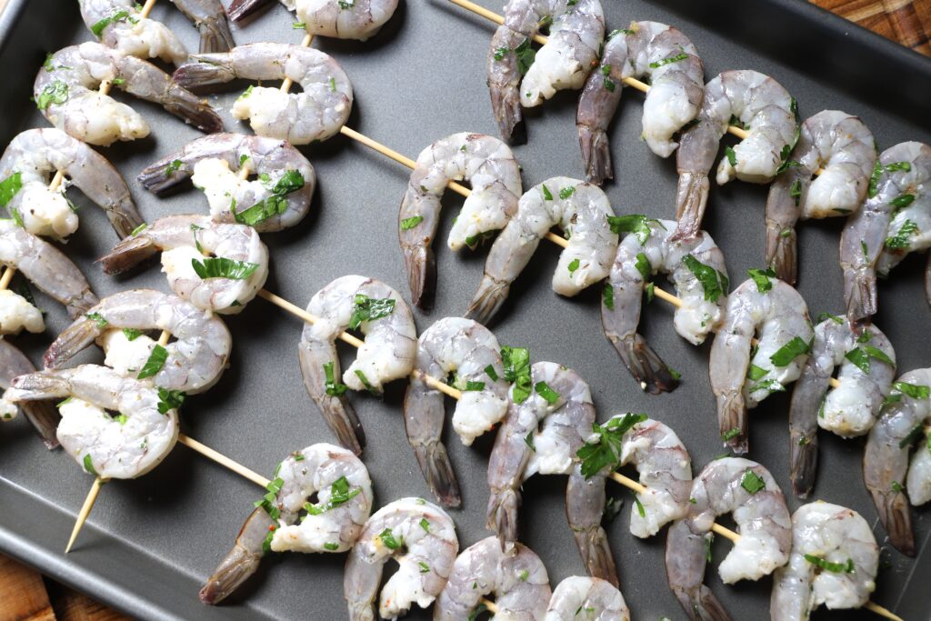 Thread shrimp onto skewers and place skewers on a prepared baking sheet.