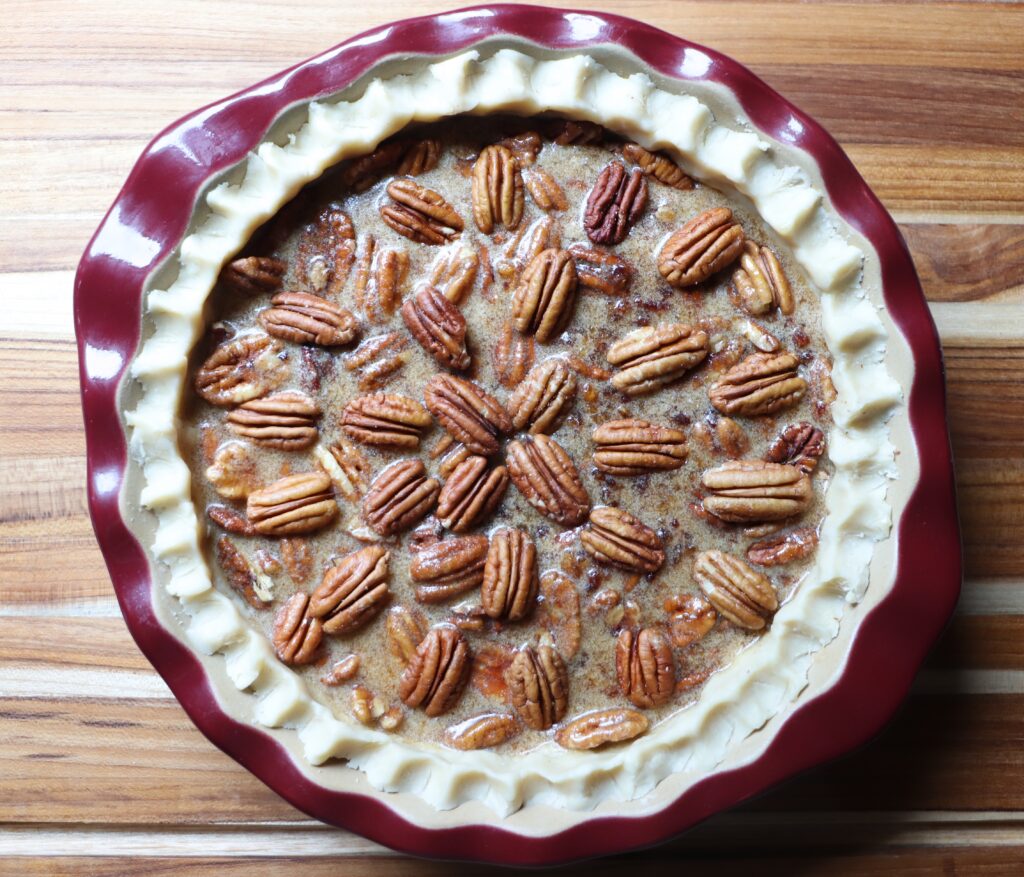 Add about 2 ½ cups of toasted pecans to the prepared pie crust and pour the egg mixture over the pecans.